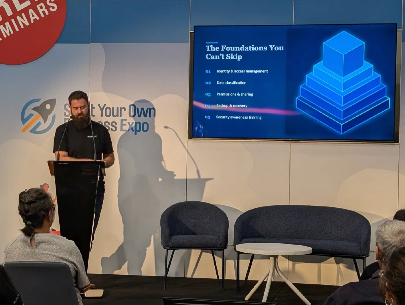 Todd Johnson presenting at a lectern beside a slide titled The Foundations You Can't Skip