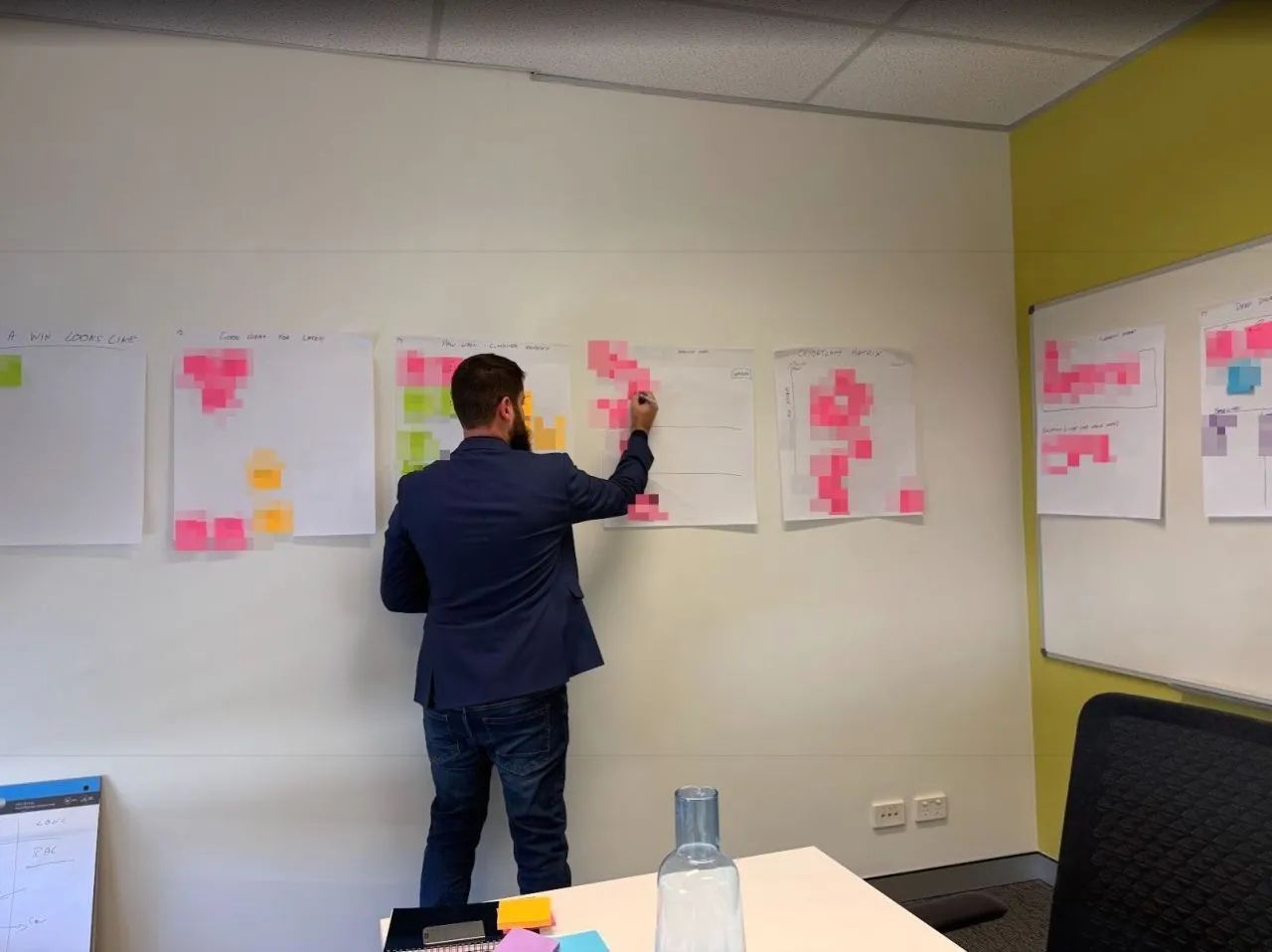 Todd Johnson writing on planning sheets covered in sticky notes during a workshop